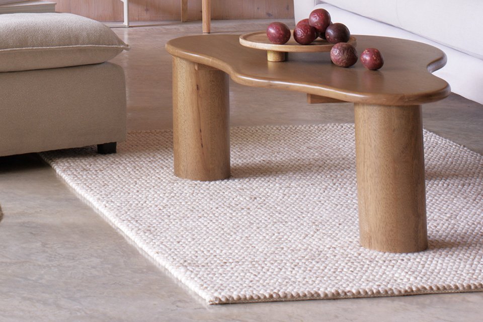 A beige rectangular rug under a table in a living room.